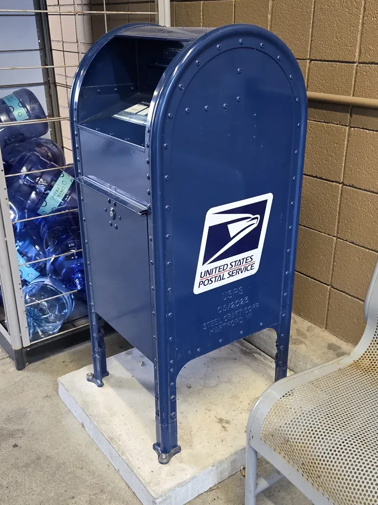 A new blue USPS collection mailbox on a city street