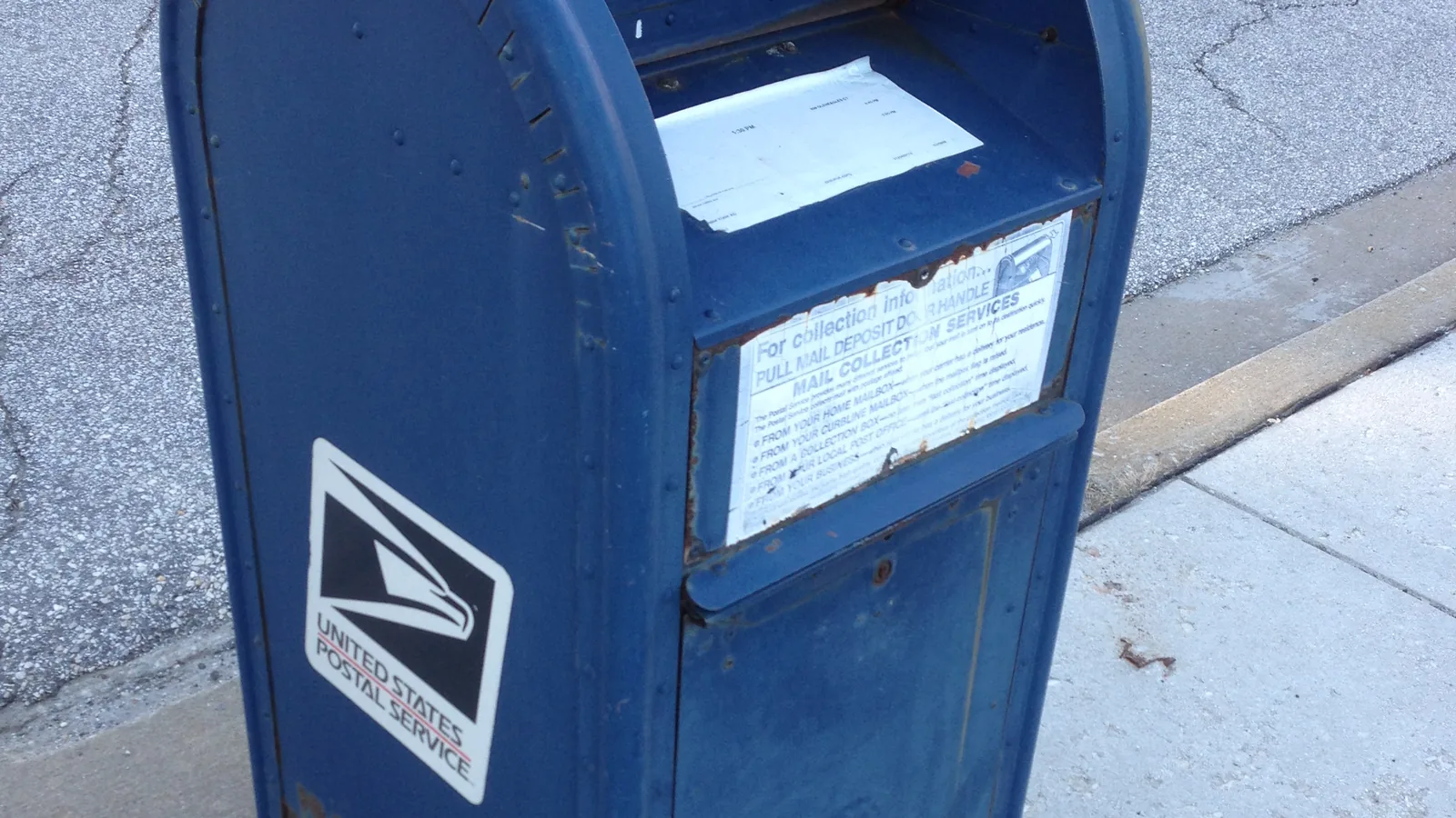 A blue USPS collection mailbox on a city street
